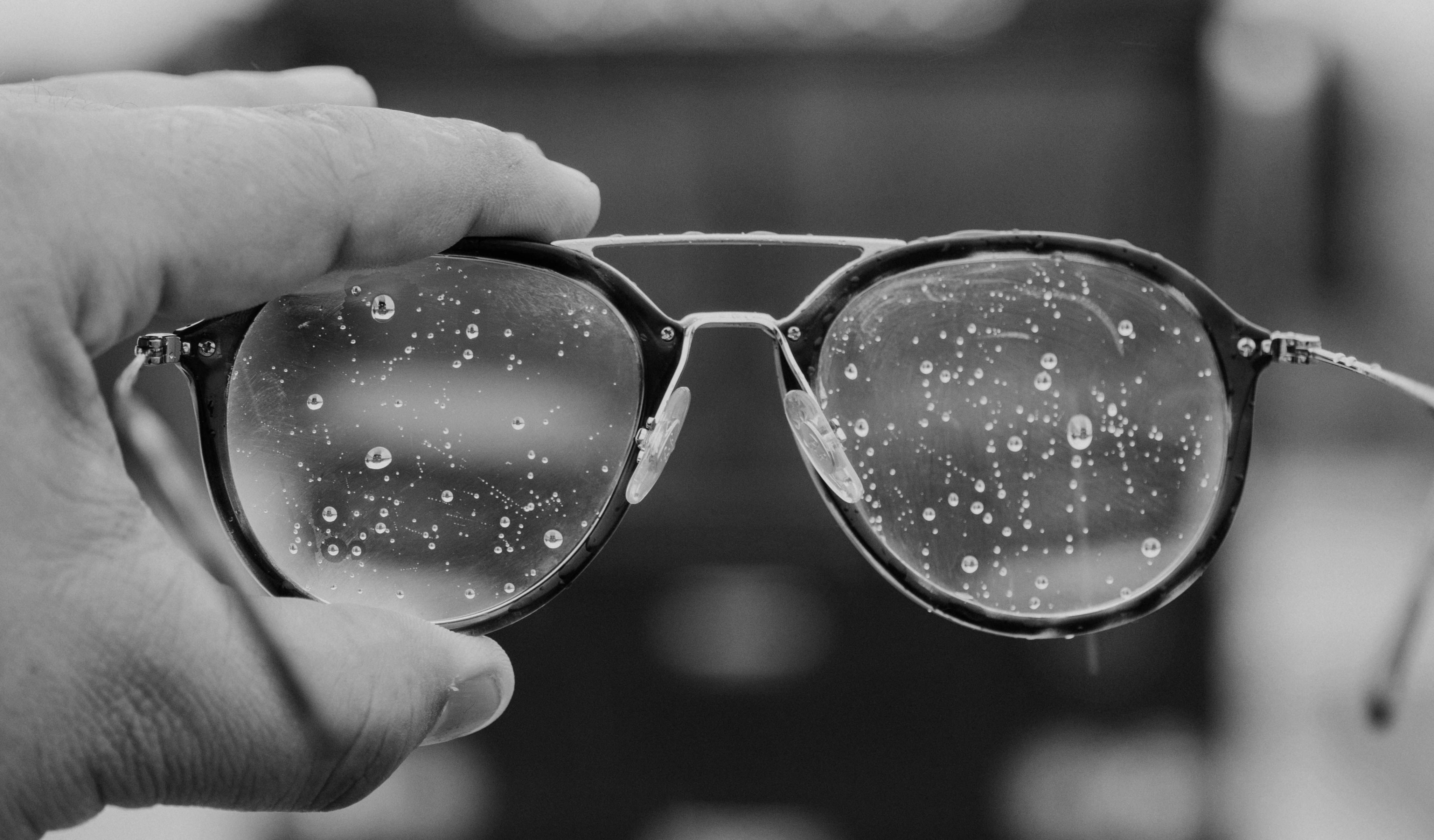 a hand holding a pair of glasses with water droplets on it